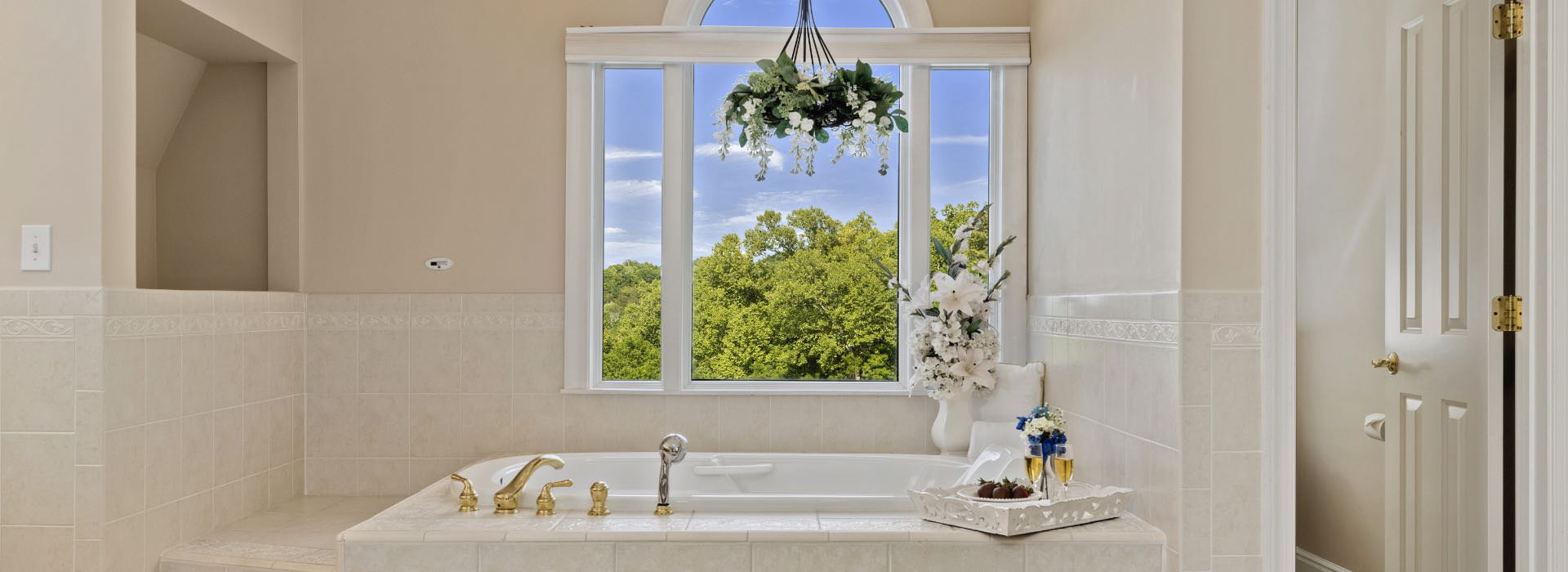 Bathroom with jetted tub, light colored tile, and view to the outside
