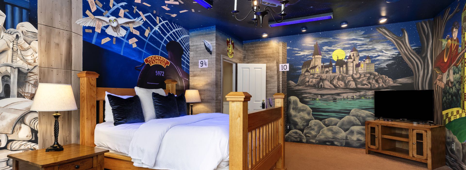 wooden queen bed with blue walls and floor to ceiling windows with Harry Potter and Hogwarts Express images painted on the walls, along with a light blue armchair