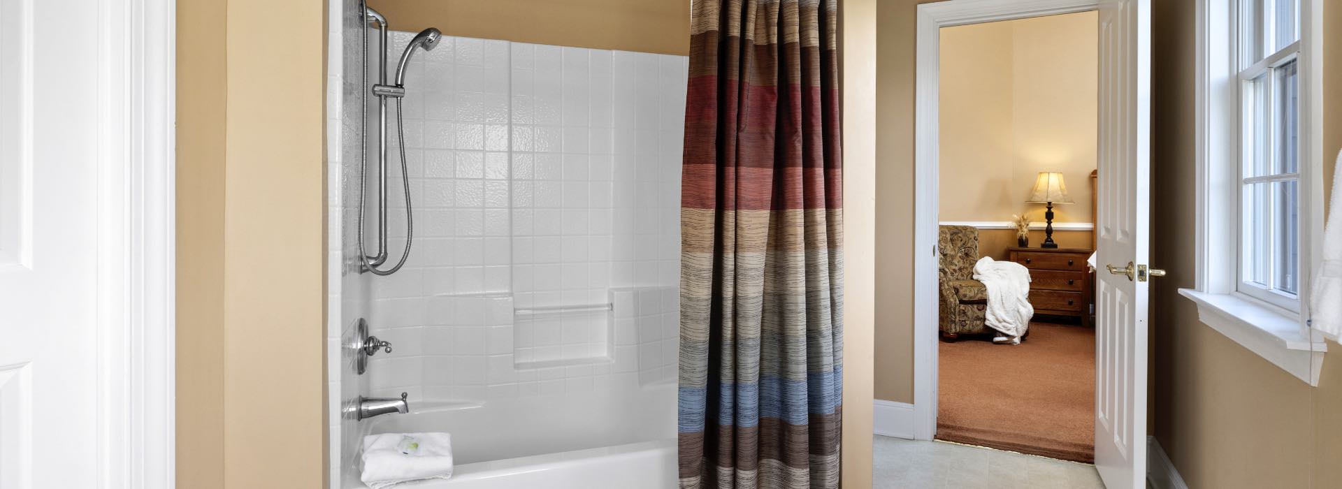 Bathroom with light colored walls, white trim, and shower/tub combo with multicolored striped curtain