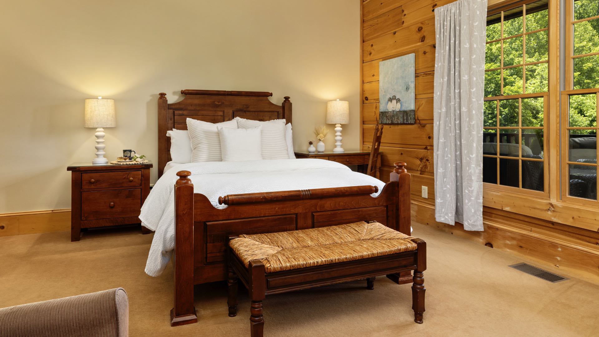 Bedroom with light yellow and wood paneled walls, wood trim, carpeting, wooden bed, white bedding, and dark wooden nightstand and desk