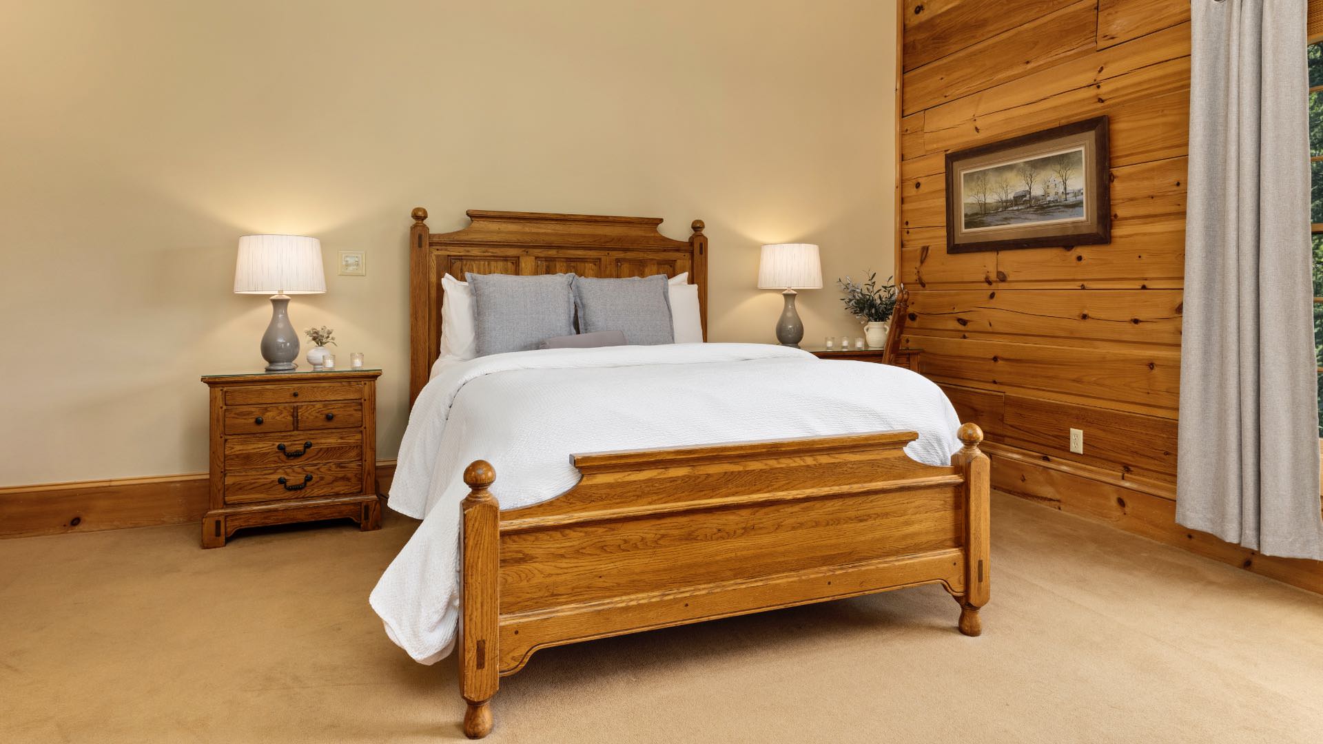 Bedroom with cream and wood paneled walls, wood trim, carpeting, wooden bed, white bedding, and wooden nightstand and desk
