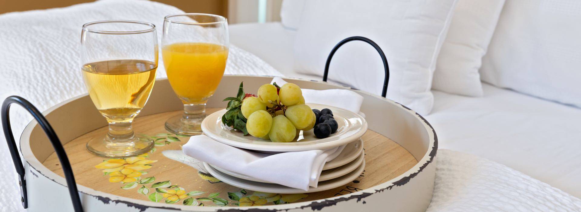 Close up view of round tray with a glass of apple juice, glass of orange juice, and small plate of fruit